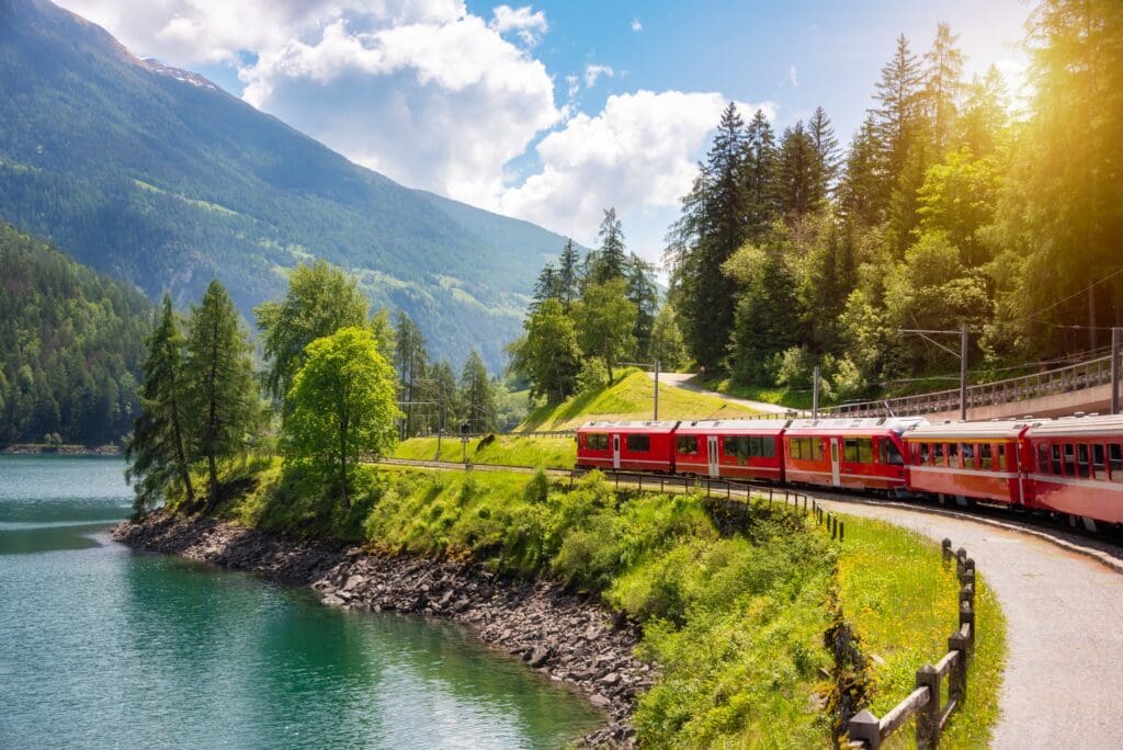 Red,Train,Moving,Along,Lake,In,Beautiful,Mountain,Landscape,In