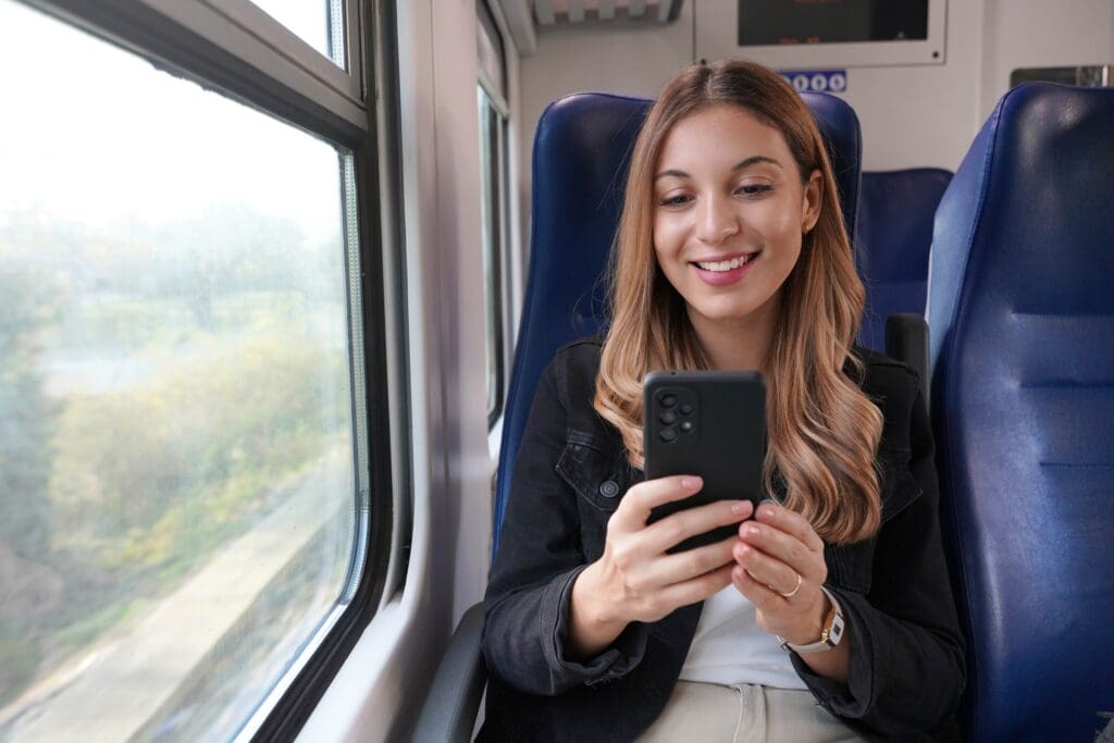 Smiling,Business,Woman,Using,Public,Transport,,Sitting,With,Cellphone,On