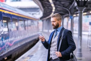 Hipster,Businessman,With,Smartphone,,Waiting,At,The,Train,Platfo