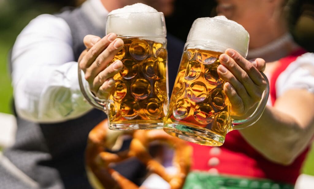 Man,And,Woman,In,Traditional,Bavarian,Attire,Clink,Large,Frothy