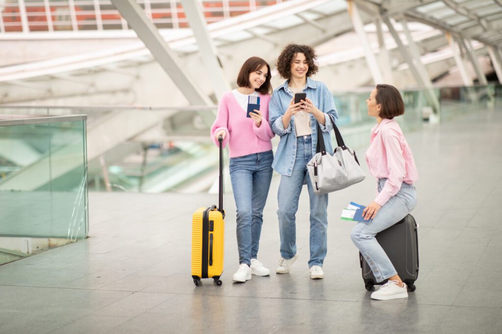 Three friends with luggage enjoying travel plans at an airport terminal