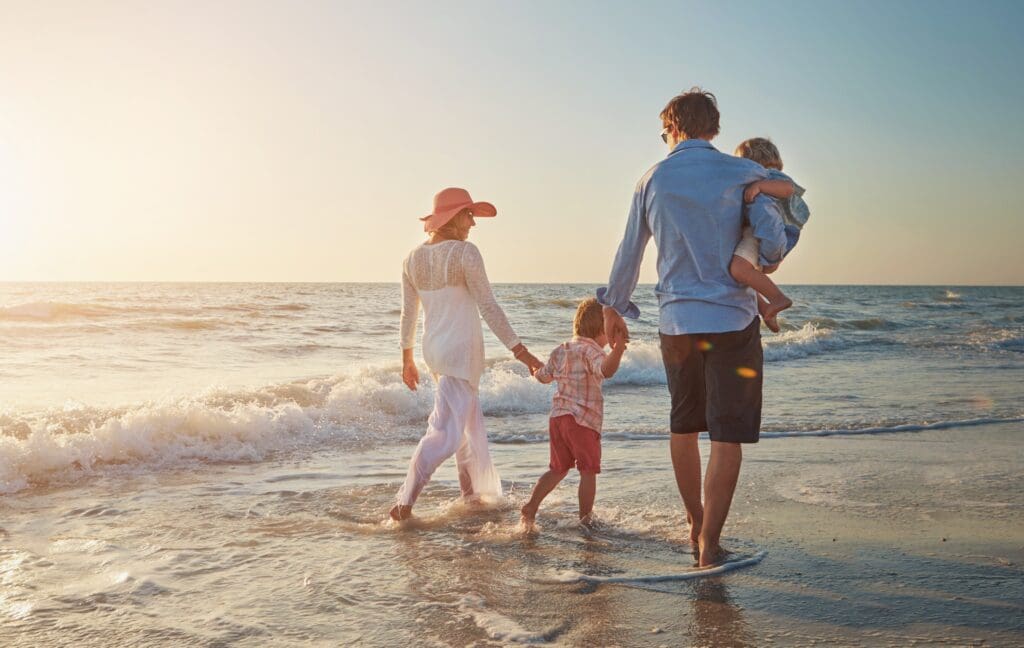 Family,,Beach,Walk,And,Back,With,Dad,Holding,Child,For